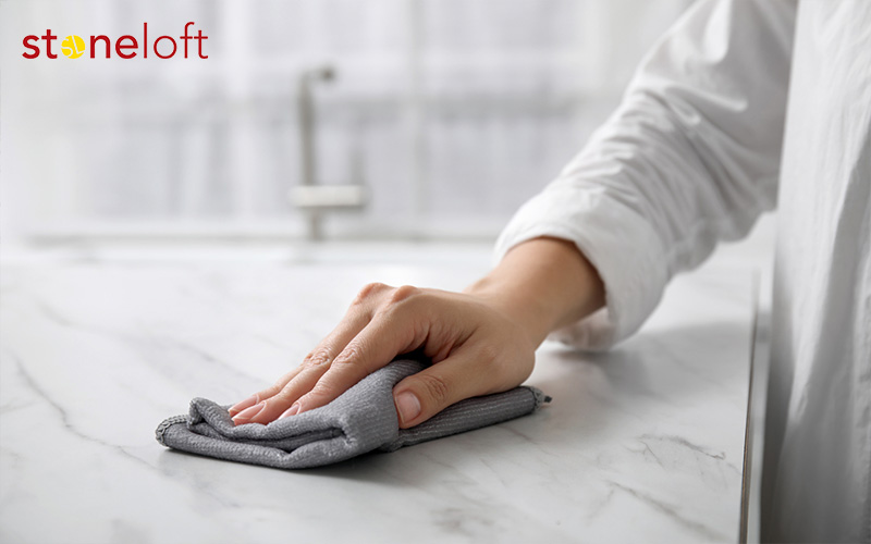 Woman cleaning a white marble kitchen countertop